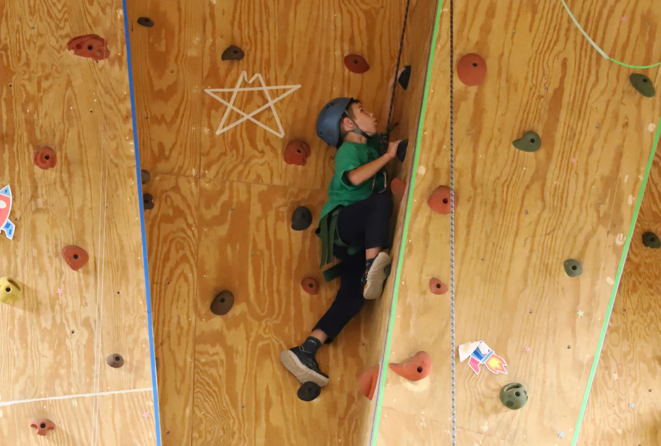 boy climbing up an indoor rock wall