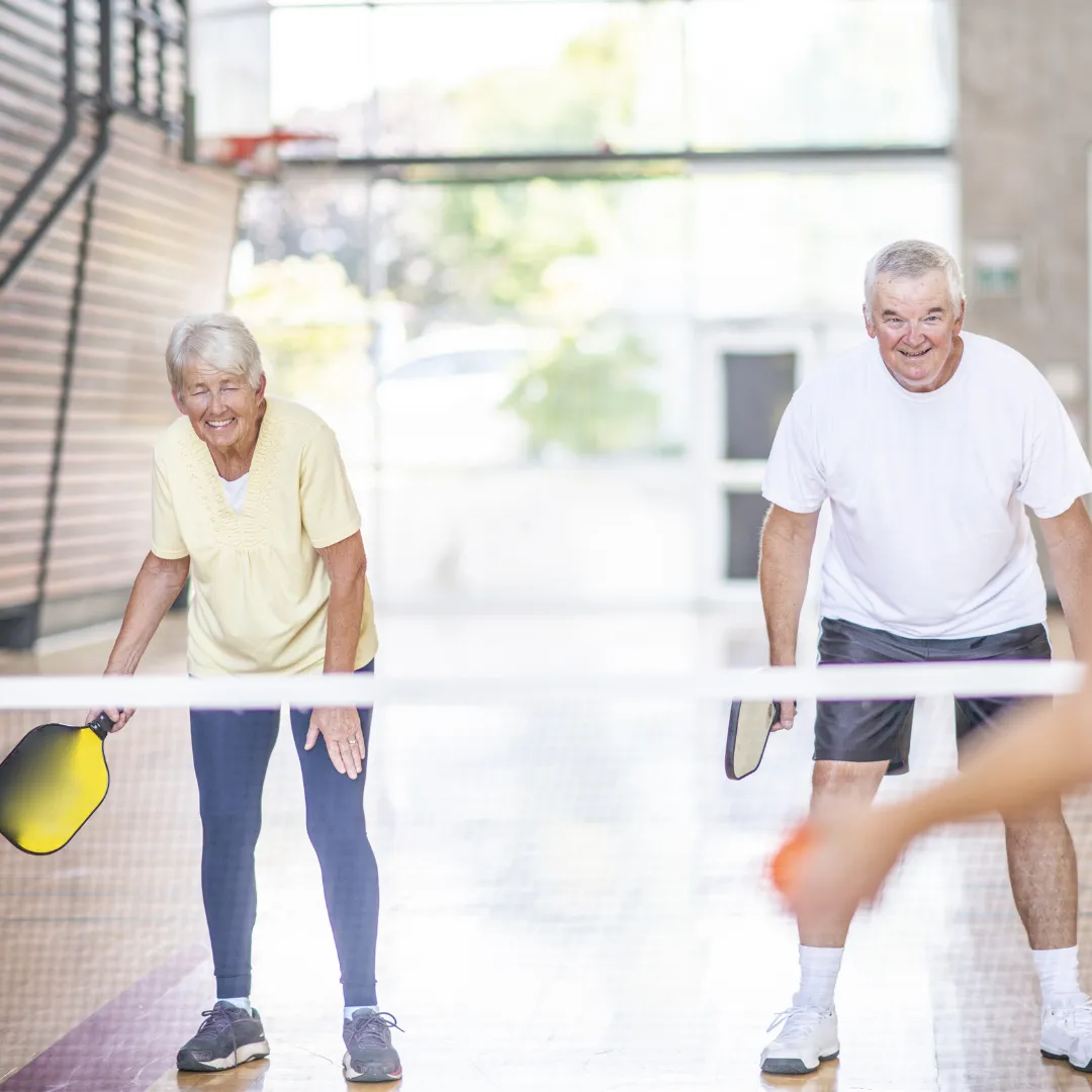 two adults playing pickleball indoors