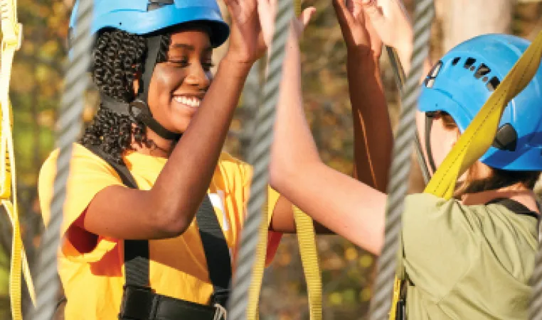 girl high fiving friend on ropes course