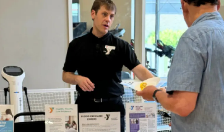 y staff member talking to older gentleman at senior health fair