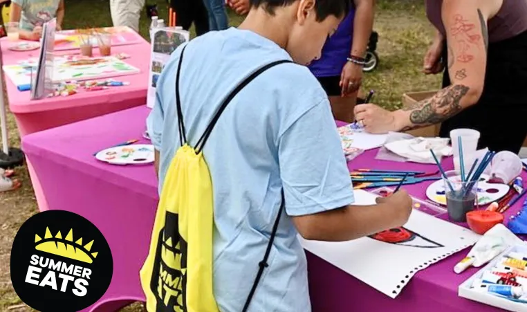 Little boy draws a picture at the Summer Eats kickoff event