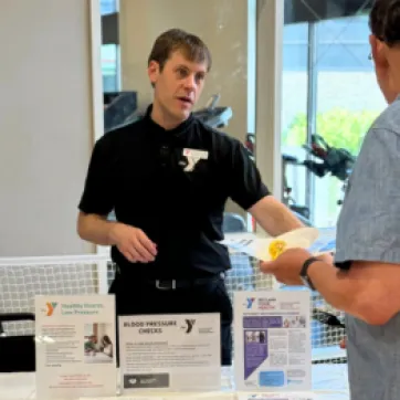 y staff member talking to older gentleman at senior health fair